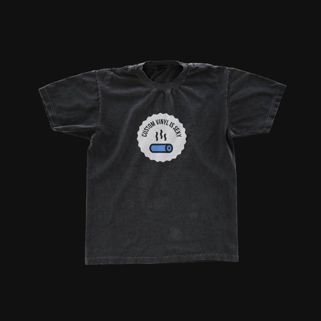 A black t-shirt with a white patch with black text and blue and black icon on it over a black background.