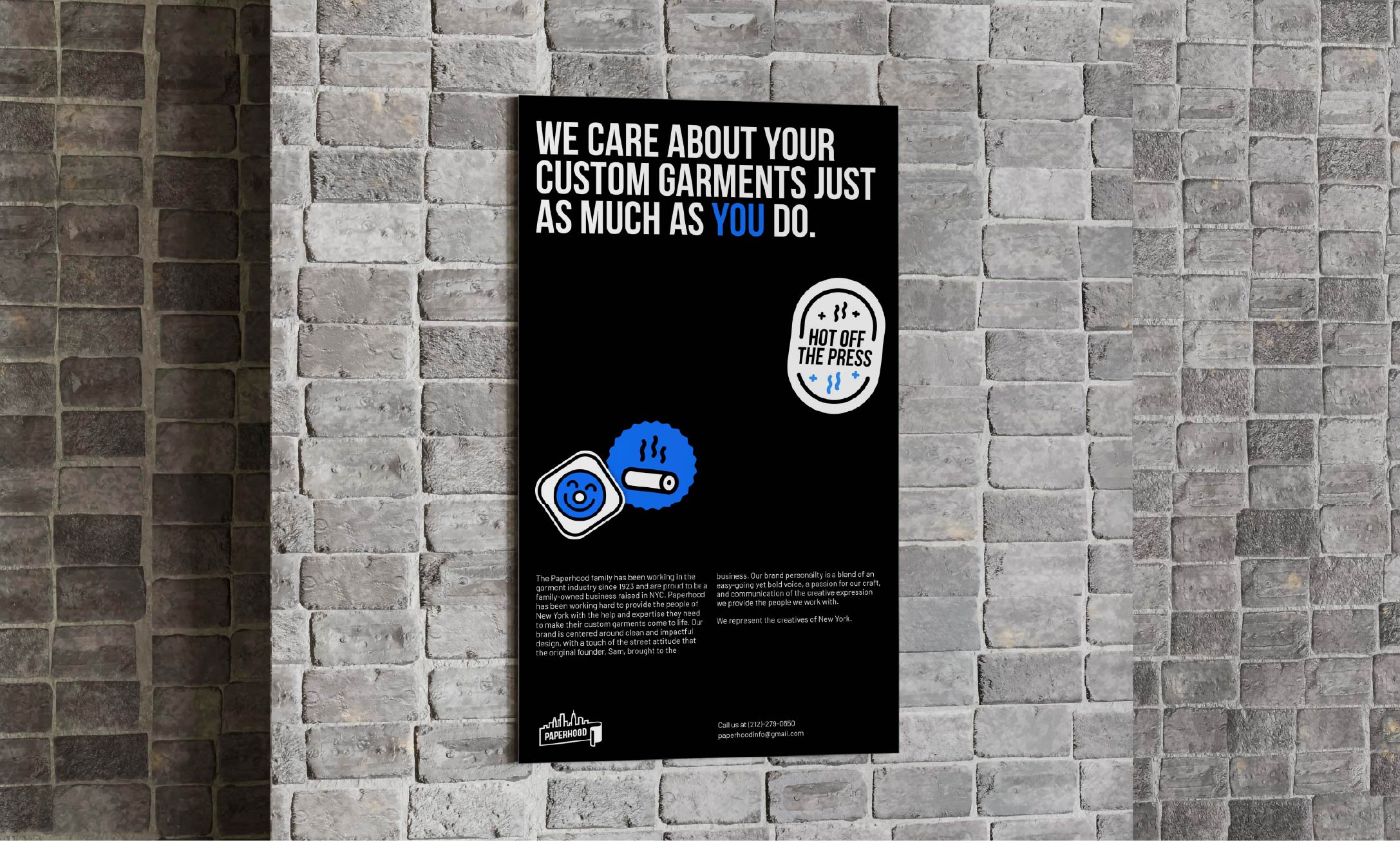 A Paperhood poster hung on a grey brick wall.