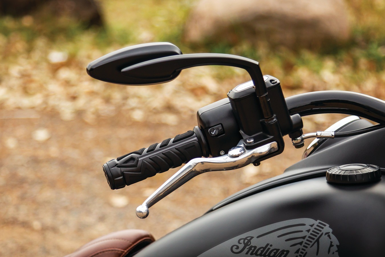A close-up view of the back of a motorcycle mirror, the finish is smooth black and there are chrome accents on surrounding parts.