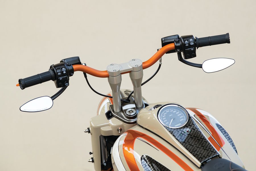 A close-up view of a motorcycle handlebar, the handlebar has orange accents.