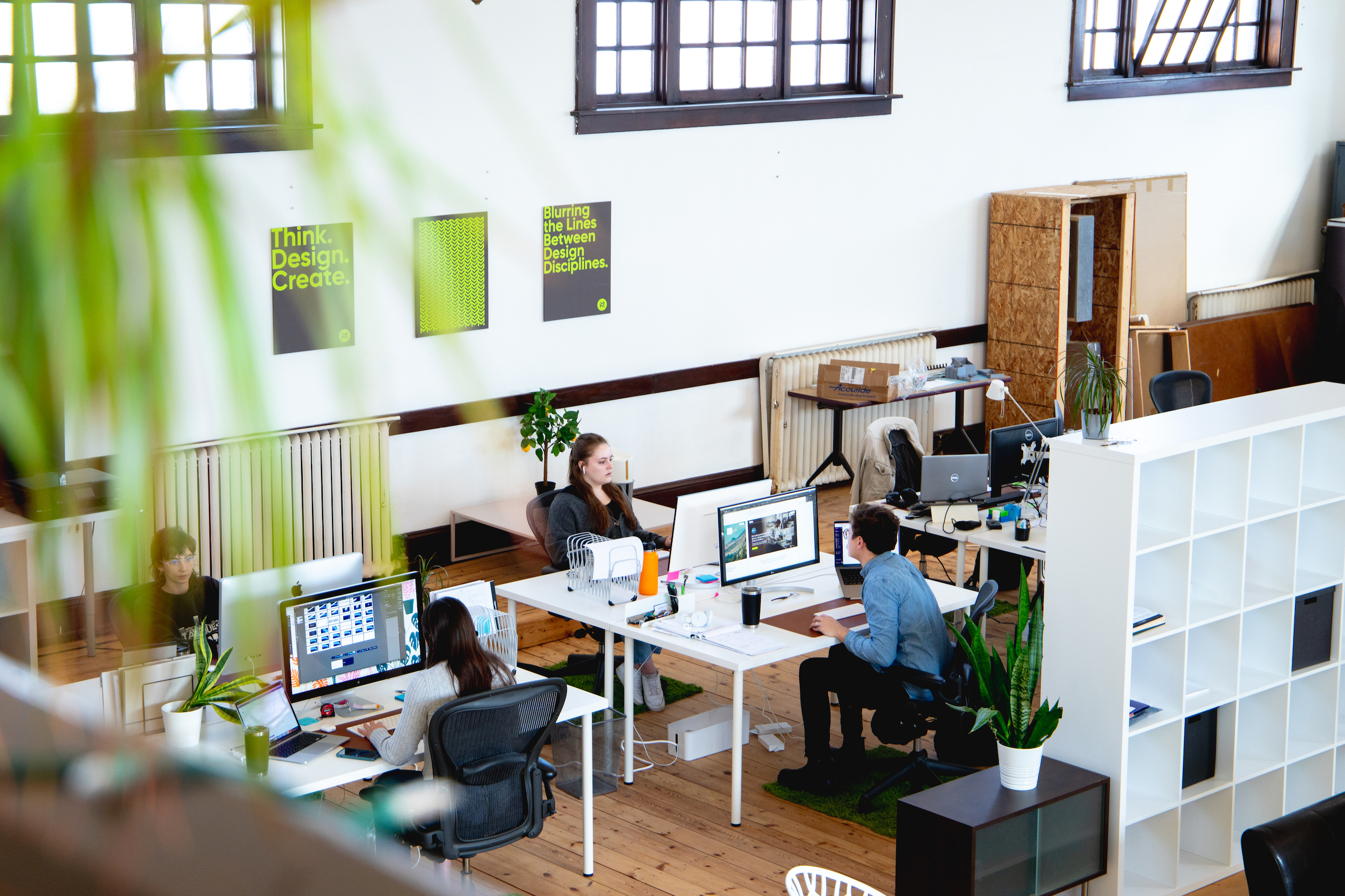 An open-concept office space with people sitting at desks and working on computers.